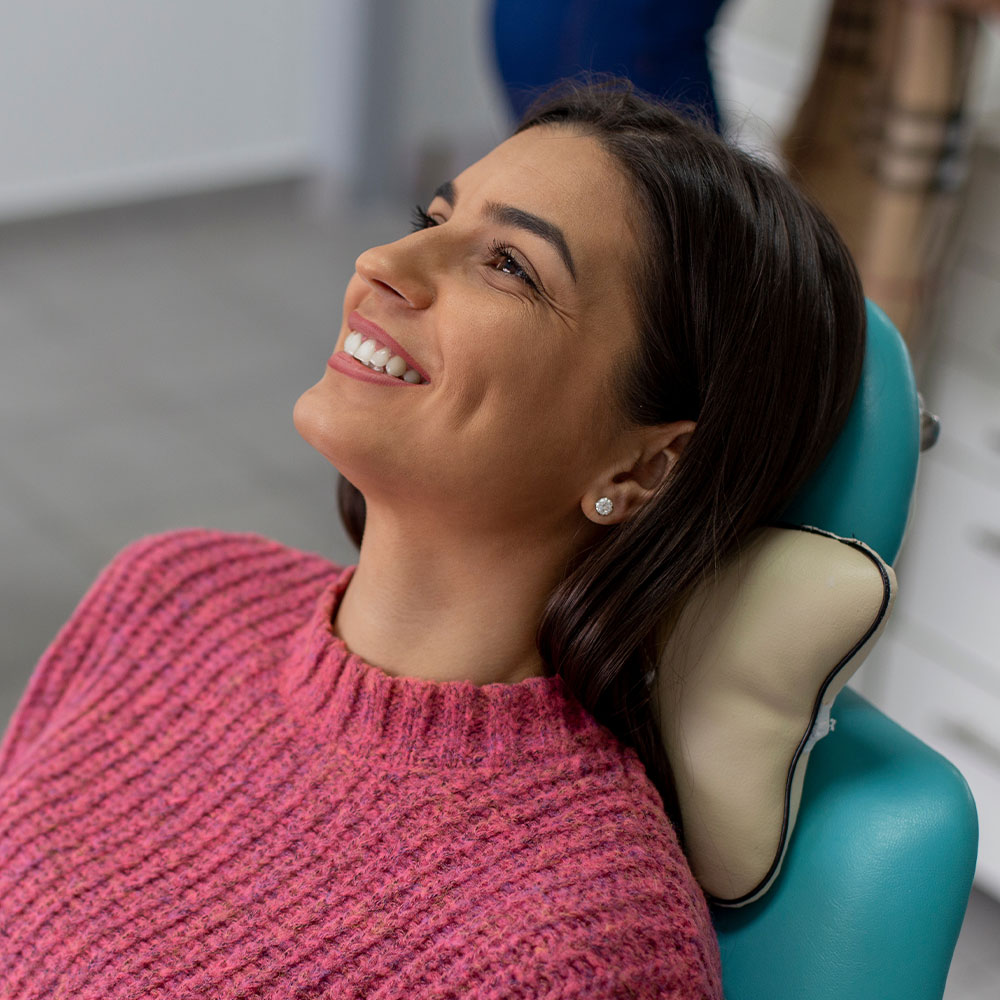 A woman sitting in a dental chair with a smile on her face.