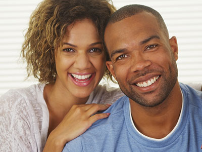 The image depicts a man and a woman sharing a joyful moment together, with the man smiling broadly at the camera and the woman laughing heartily beside him.
